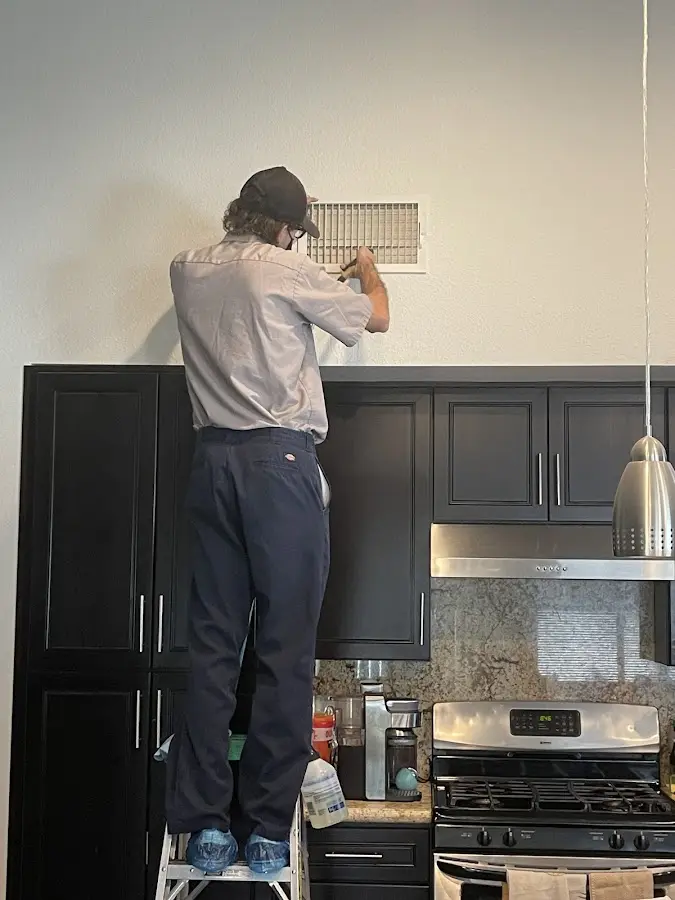 Technician inspecting an air vent during HVAC service in Cloverleaf